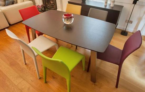 طاولة بنية خشبية وكراسي بألوان مختلفة